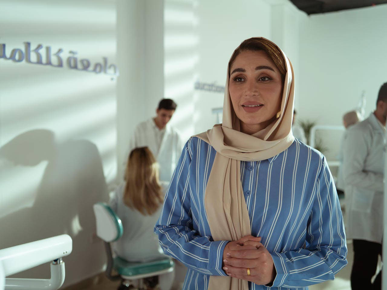 services-02 Woman in a striped shirt in an office with colleagues in the background.